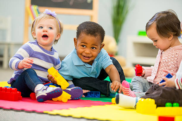 Three toddlers boy sit and play whilst laughing