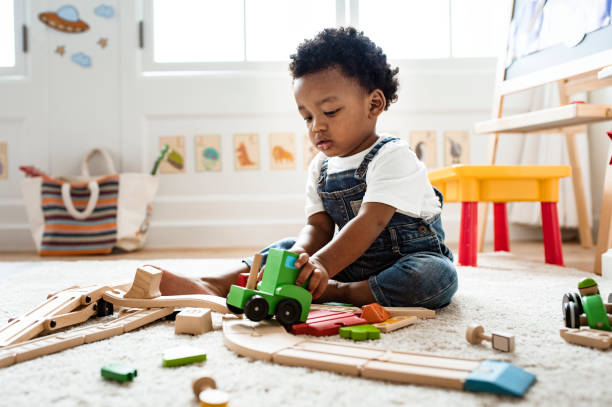 A toddler girl is pictured sitting and playing with toys